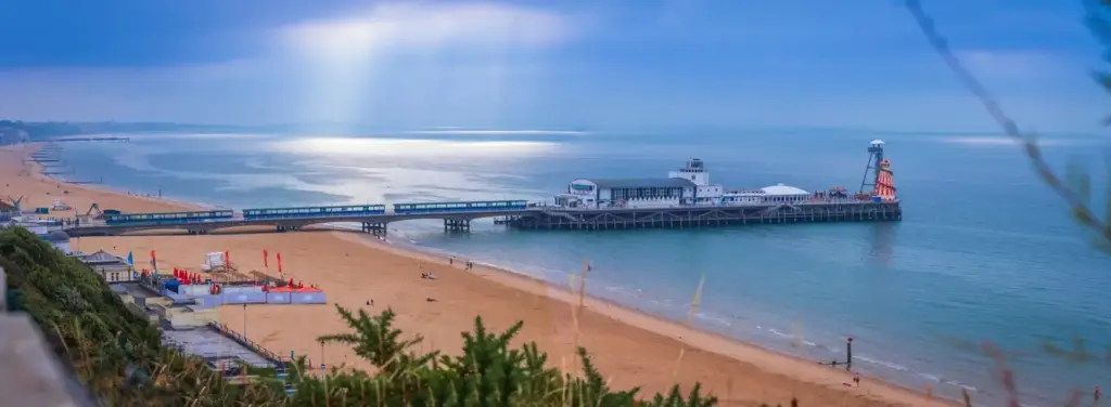 A scenic view of Bournemouth Pier, with turquoise waters and golden sandy beach stretching along the coastline.