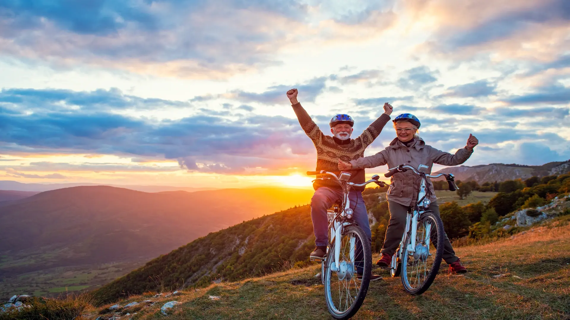 Couple cycling towards a sunset, embracing the positive psychological impact of downsizing by focusing on health and new experiences.